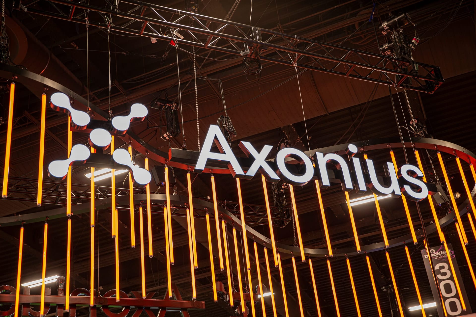 Axonius hanging sign surrounded by glowing orange light tubes above the booth