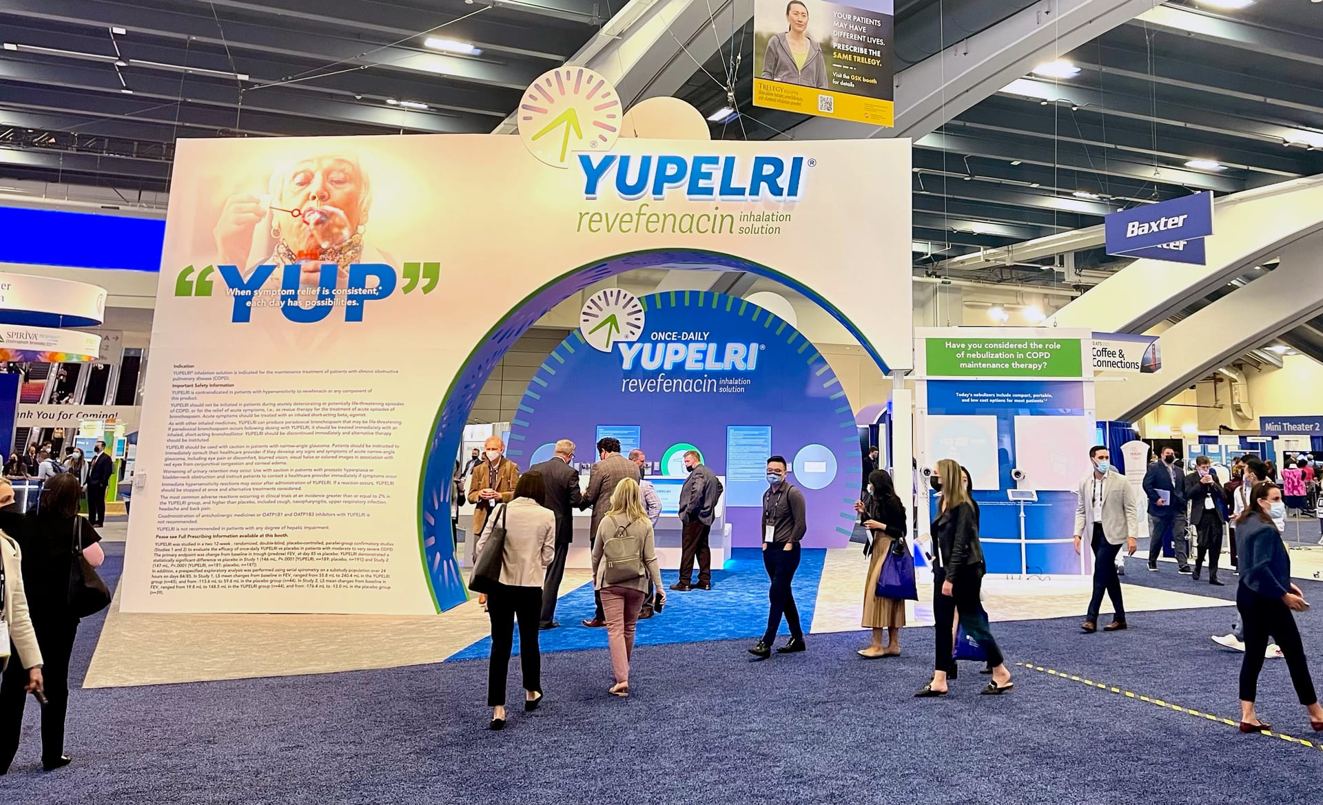 The Yupelri arch and YUP quote wall at Viatris's ATS 2022 booth, seen from the aisle with attendees walking in