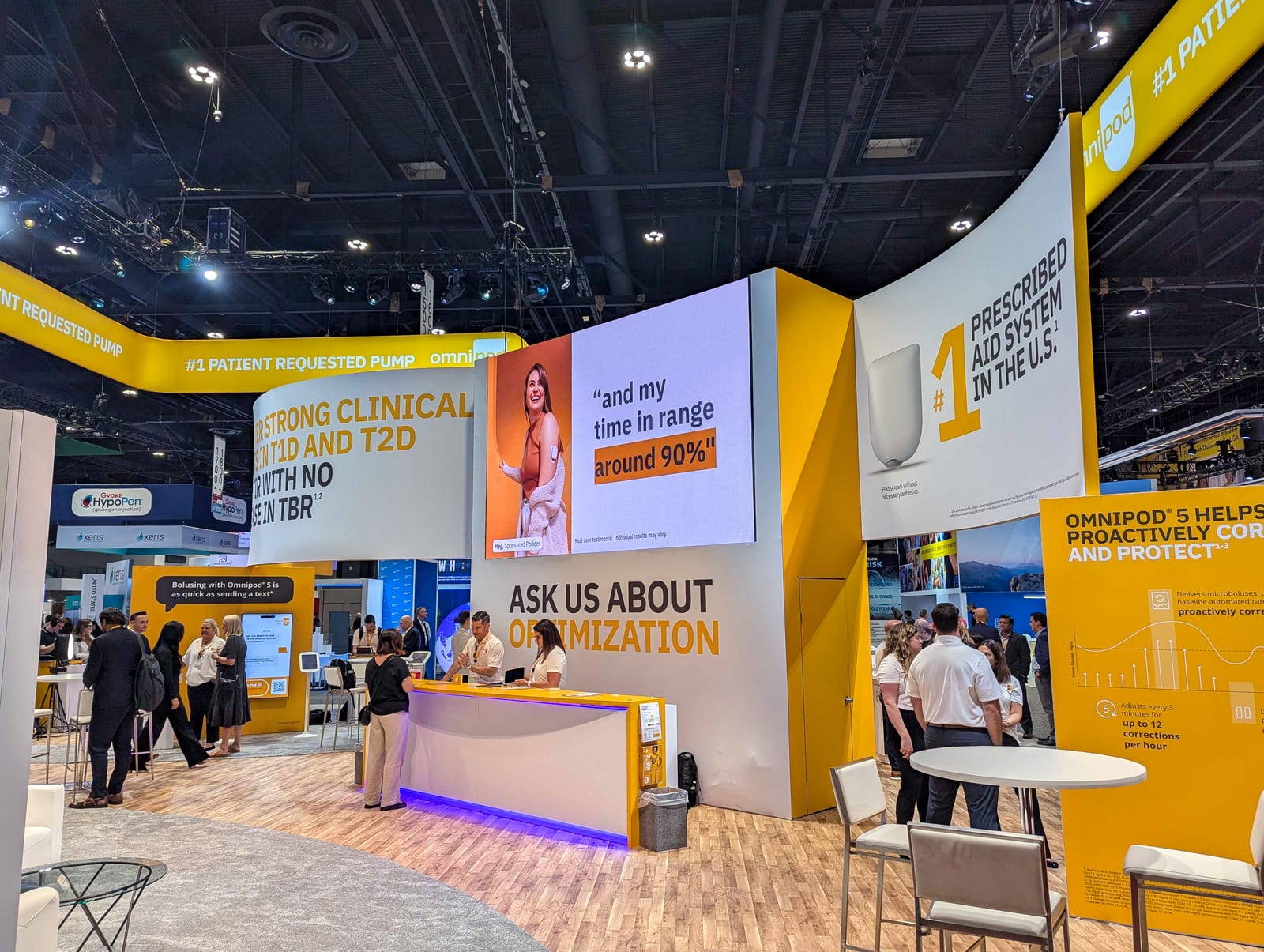 The Insulet Omnipod booth at ADA 2025 with a wide LED video wall, a reception counter, and yellow Omnipod branding