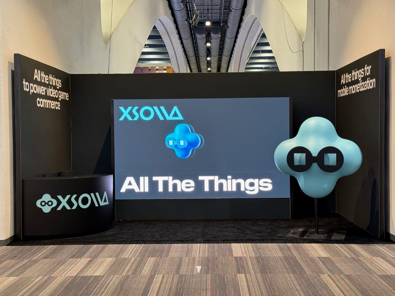 Xsolla LED wall reading 'All The Things' beside the Xsolla mascot
