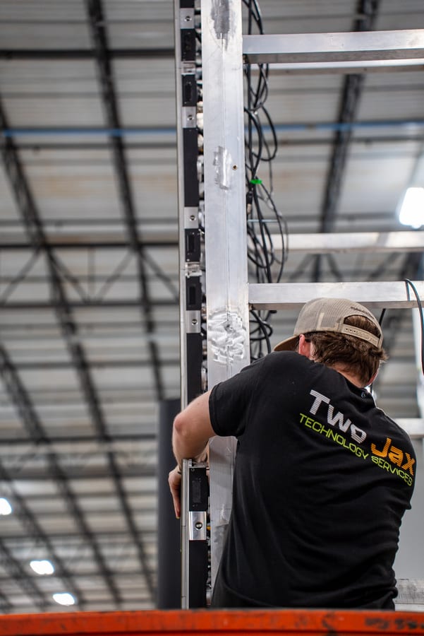A technician cabling a rack column in the shop